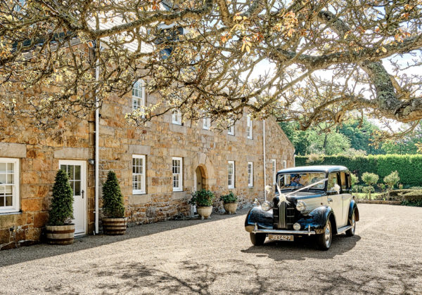 Classic car in courtyard of traditional Jersey farmhouse at La Mare Wine Estate Vineyards