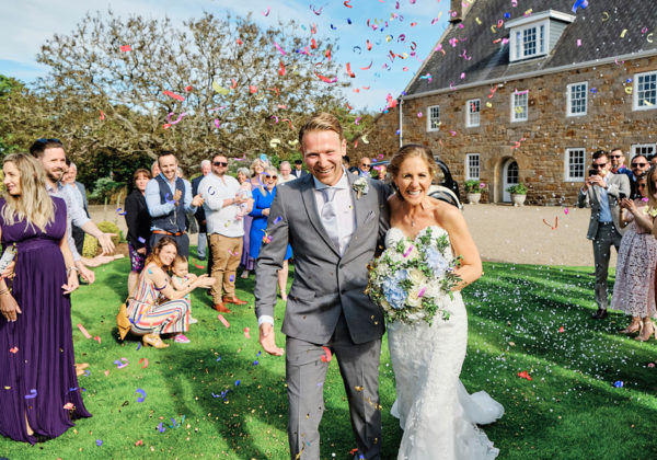 Bride and groom celebrating outside the traditional Jersey Farmhouse at La Mare Wine Estate