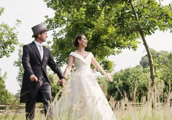 Couple in the apple orchards holding hands next to wedding car at La Mare Wine Estate